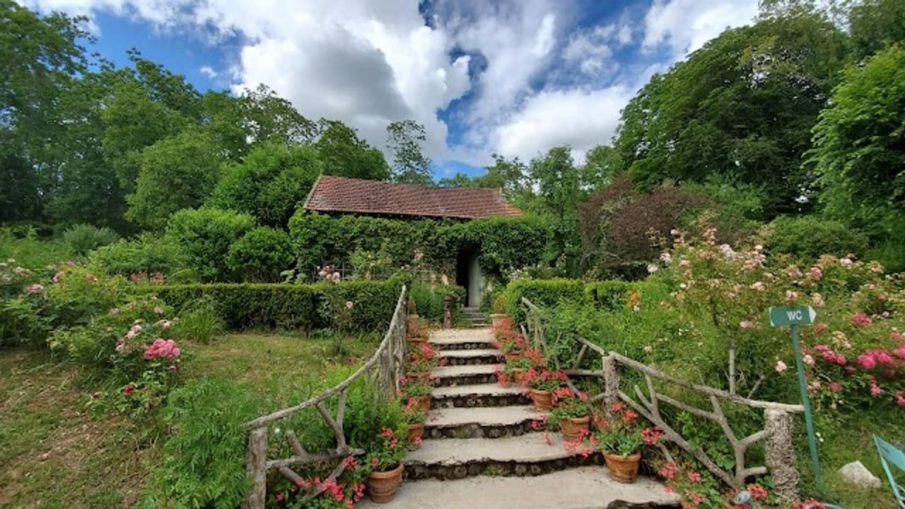 L’atelier vu depuis le bas du jardin, au sommet d’un escalier de pierre bordé de géraniums en pots