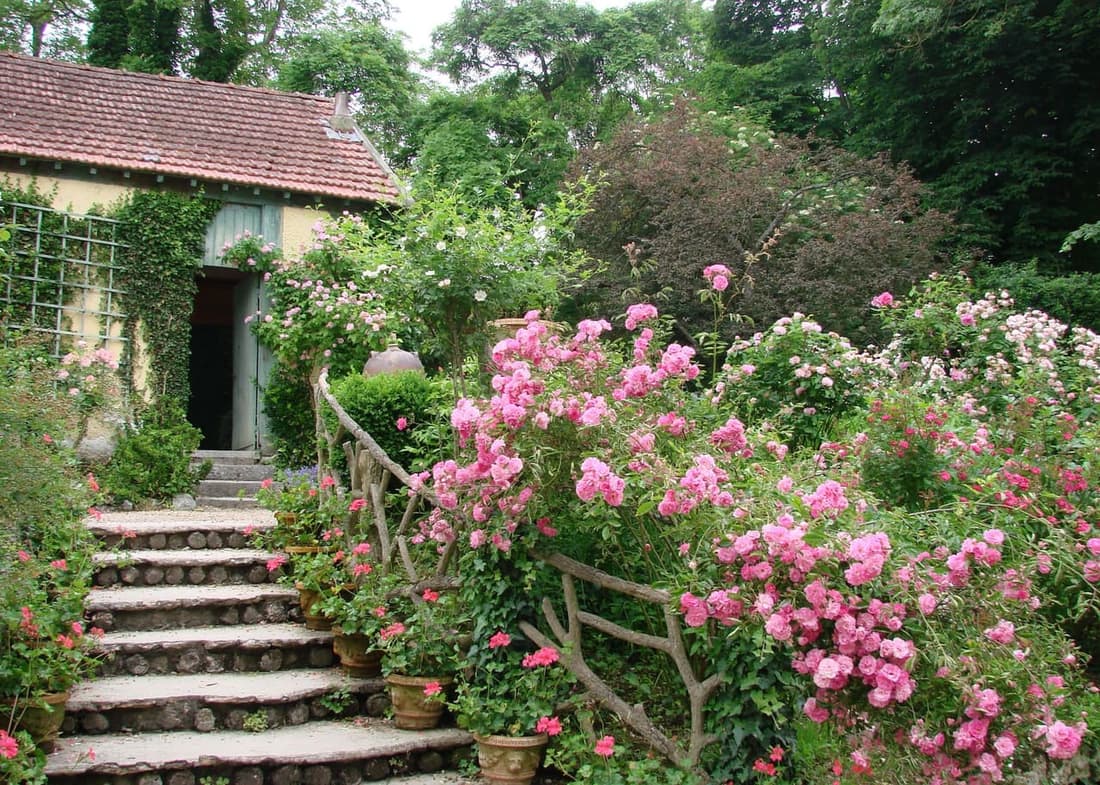Les jardins de l’Hôtel Baudy aujourd’hui : un escalier de pierre bordé de rosiers en fleurs monte vers l’atelier