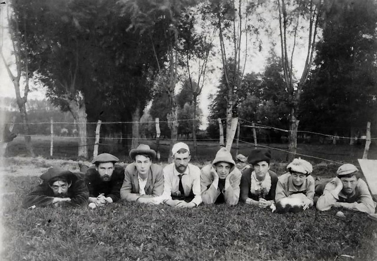 Photographie ancienne : huit hommes allongés dans une prairie bordée de peupliers